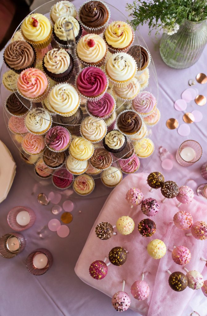 A tiered stand displaying colorful cupcakes and cake pops.