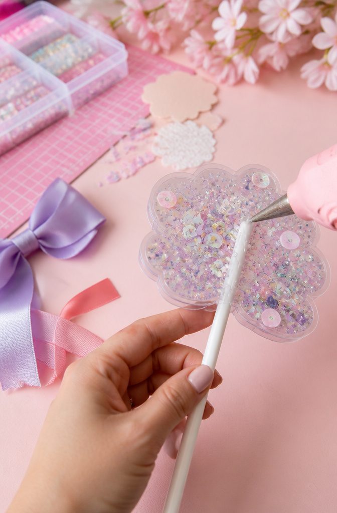 How to Make a Cake Topper Shaker: 3 Item Sections for Fillers 7 A lollipop stick being glued to the back of a cake topper shaker.