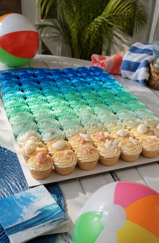 Cupcakes arranged to depict a beach scene with blue and cream frosting.