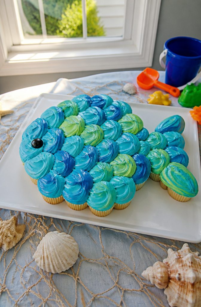 Cupcakes arranged to form a fish with blue and green frosting.