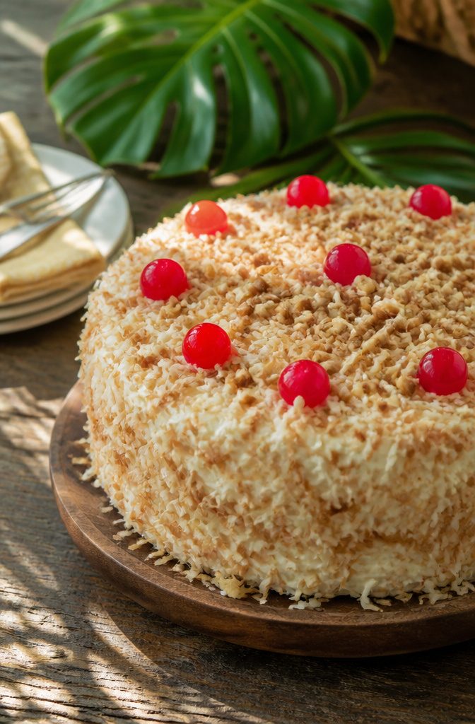 Close-up of Hawaiian wedding cake with toppings of coconut and cherries.